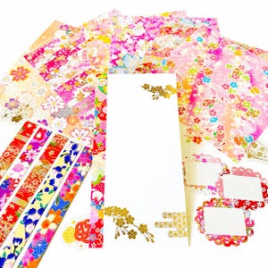 以下が含まれることがあります： ピンク、赤、ゴールドの色合いで鮮やかな花柄が描かれた装飾用ステーショナリーセット。長方形のシート、細長い帯、スカラップ型のラベルが含まれており、すべて精巧な花模様と金箔のアクセントで装飾されています。