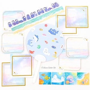 May include: A stationery set featuring a light blue fan with sea creature illustrations, notepads with gold borders, and decorative tape with penguin designs. The set includes the text "Uchiwa Letter Set", "Thank you", and "Just for you".