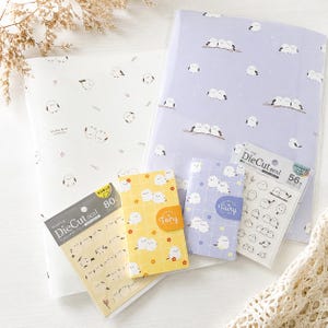 May include: A collection of stationery items featuring small white birds, including two large sheets of paper, two packs of masking die-cut seals, and two small notebooks in yellow and purple with grid patterns and bird illustrations.