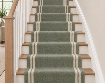 May include: A sage green stair runner with two vertical cream-coloured stripes running down the centre. The runner is installed on a wooden staircase with white railings and light brown wooden treads, covering the middle section of each step.