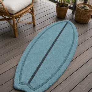 May include: A light blue, surfboard-shaped rug featuring a dark blue central stripe and a matching dark blue border outline. The rug has a textured, tufted surface and a classic surfboard silhouette with a rounded nose and a notched tail design.