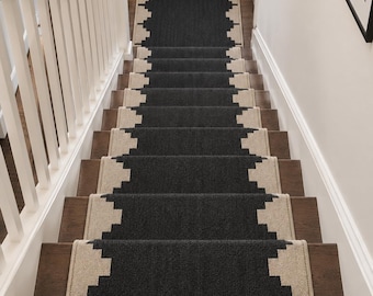 May include: A long stair runner rug featuring a dark charcoal grey centre with a repeating geometric stepped pattern in cream along both edges, installed over dark brown wooden stairs in a straight vertical orientation.