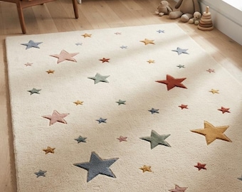 May include: A rectangular area rug with a cream-coloured background featuring a scattered pattern of five-pointed stars in various sizes and muted tones, including dusty pink, sage green, mustard yellow, terracotta, and slate blue.