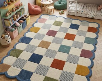 May include: A rectangular area rug with a scalloped edge featuring a grid pattern of cream-coloured squares interspersed with solid squares in blue, mustard yellow, olive green, rust orange, and maroon, along with textured striped squares.