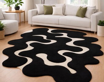 May include: An area rug with an irregular, organic shape featuring a high-contrast pattern of black and cream-coloured wavy, interconnected lines. The rug has a thick, textured pile and covers a portion of the light-coloured wooden floor.