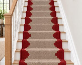 May include: A stair runner featuring a textured beige centre panel bordered by a bold red geometric pattern. The runner covers the centre of a wooden staircase with white risers and a wooden handrail, extending from the bottom to the top landing.