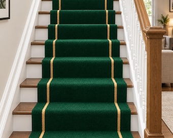 May include: A dark green stair runner with two vertical beige stripes running down the centre, installed on a wooden staircase with white risers and a wooden handrail. The carpet covers the treads of the stairs in a straight, uniform alignment.