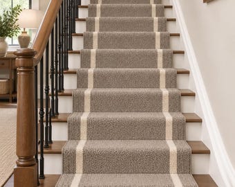 May include: A staircase featuring a textured taupe carpet runner with a central cream stripe and a fringed edge at the bottom. The stairs have dark wooden treads and white risers, complemented by a wooden handrail and black metal balusters.