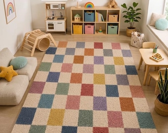 May include: A rectangular area rug featuring a repeating checkerboard pattern of textured squares in cream, blue, pink, yellow, green, purple, and terracotta colours, covering the floor of a room with light wood flooring and furniture.