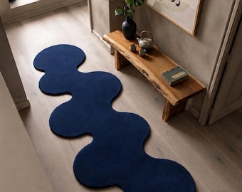 May include: A long, deep navy blue runner rug featuring a series of interconnected, rounded, cloud-like shapes. The rug has a solid, uniform colour and a textured, tufted surface, extending across the floor in an organic, flowing, non-linear pattern.