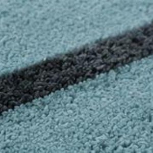 May include: A textured fabric surface featuring a light blue base with a prominent diagonal stripe in dark charcoal grey. The material has a dense, looped pile construction that creates a soft, uneven appearance across the entire textile surface.