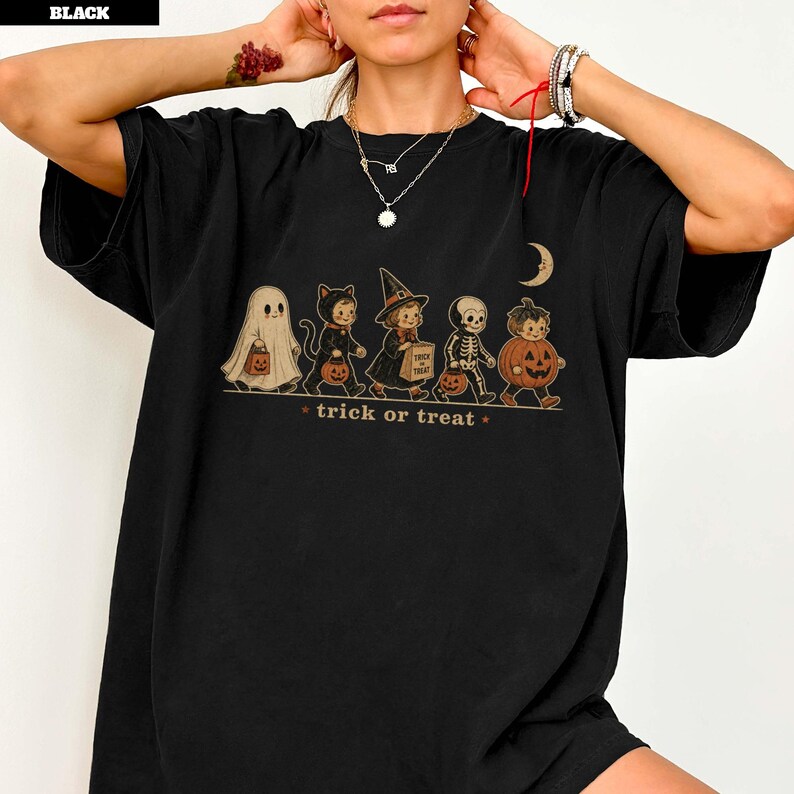 Black t-shirt with Halloween characters dressed as a ghost, cat, witch, skeleton, and pumpkin.