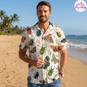 May include: A short-sleeved button-down shirt in off-white featuring a colorful all-over print of various beetles, moths, and butterflies interspersed with small green sprigs and tiny star shapes, designed with a classic collar and front buttons.