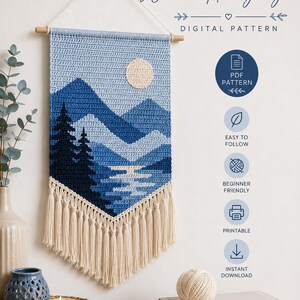 Puede incluir: Un tapiz de pared de ganchillo hecho a mano con un paisaje de montaña en tonos azules, con un sol beige y flecos. El texto dice "CROCHET Wall Hanging" y "DIGITAL PATTERN". El diseño es apto para principiantes y se puede imprimir.