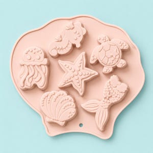 May include: A light pink silicone mold shaped like a large seashell, featuring six recessed cavities in the forms of a jellyfish, a seahorse, a sea turtle, a starfish, a seashell, and a mermaid tail, with a small circular hole at the bottom.