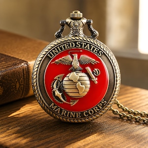 Op de afbeelding: Een vintage zakhorloge met een bronzen afwerking en een ketting. De wijzerplaat toont het embleem van het United States Marine Corps, met een adelaar, wereldbol en anker op een rode achtergrond. De woorden "United States Marine Corps" zijn gegraveerd.
