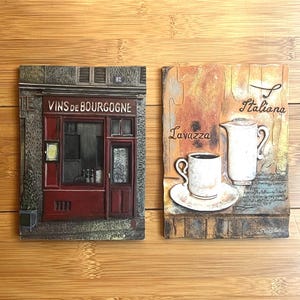 May include: Two rectangular wall plaques. The left plaque depicts a storefront with a dark red facade, a window, and the text VINS DE BOURGOGNE and 82. The right plaque features a white coffee cup on a saucer, a white pitcher, and the text Lavazza Italiana.
