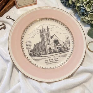 May include: A vintage decorative plate with a pink border and a gold rim. The center features a black and white illustration of a church with the text "First Baptist Church 700 E. Berkley Avenue Norfolk, Virginia."