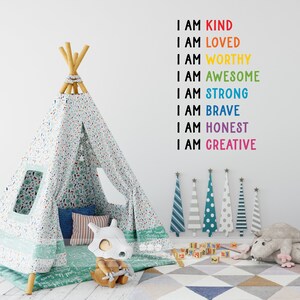 May include: A white teepee tent with a green and white floral pattern, a grey and white striped pillow, a brown and white pillow, and a toy dinosaur. The wall behind the teepee has a rainbow of words that say "I am kind, I am loved, I am worthy, I am awesome, I am strong, I am brave, I am honest, I am creative."