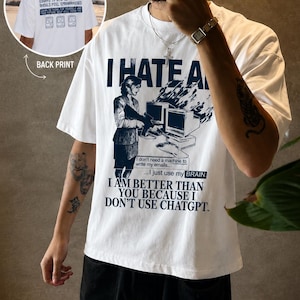 Può includere: Una t-shirt bianca con una stampa grafica blu scuro sul davanti e sul retro. Il davanti mostra una persona al computer con il testo I HATE AI, I don't need a machine to write my emails, I just use my BRAIN, e I AM BETTER THAN YOU BECAUSE I DON'T USE CHATGPT. La stampa sul retro include il testo USING AI TO WRITE YOUR ESSAYS IS STUPID AND YOU SHOULD FEEL EMBARRASSED.