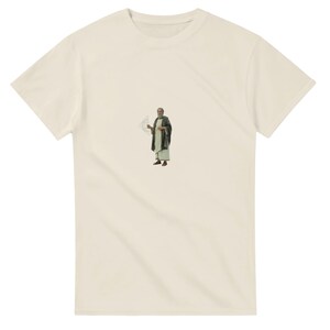 Peut inclure: T-shirt crème avec un petit graphisme d'un homme en robe tenant un parchemin. Le graphisme est au centre du t-shirt. Le t-shirt a des manches courtes et un col rond.