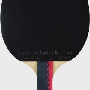 Op de afbeelding: Een zwarte tafeltennisbat met de merknaam "Butterfly" en de naam "Yuki" op het bat gedrukt. Het handvat is een combinatie van beige, marineblauw en rood. Het nummer "303" is op het handvat gedrukt.