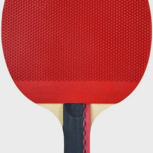 Op de afbeelding: Een rode tafeltennisbat met een getextureerd oppervlak. De handgreep is donkerblauw met een roze en rode streep in het midden. De bat is ontworpen voor tafeltennis.