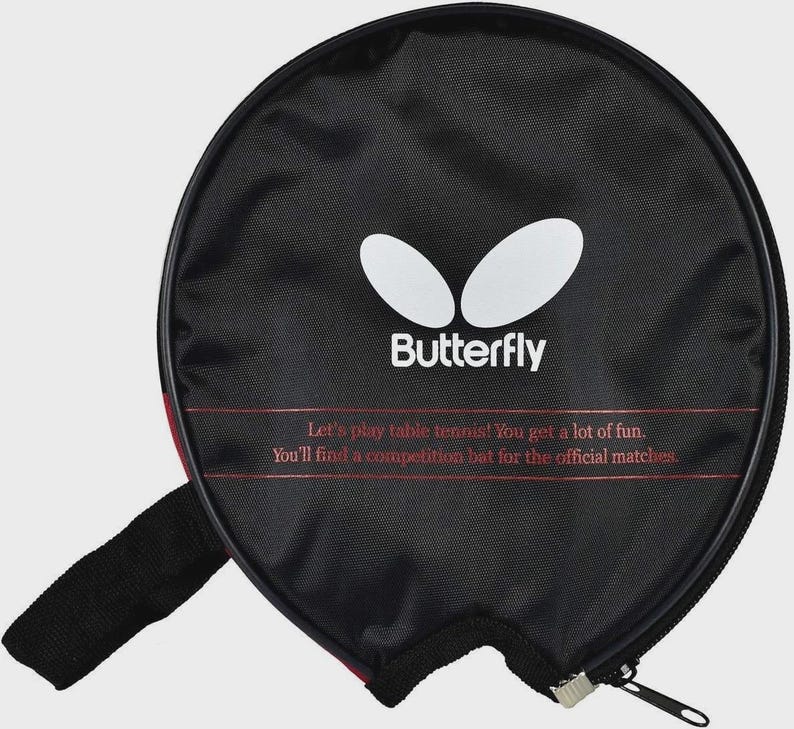Op de afbeelding: Zwarte tafeltennisracketcase met het "Butterfly" logo en tekst. De case heeft een ritssluiting en een zwarte handgreep. De tekst luidt: "Laten we tafeltennis spelen! Je hebt veel plezier. Je vindt een competitiebat voor de offici&euml;le wedstrijden."