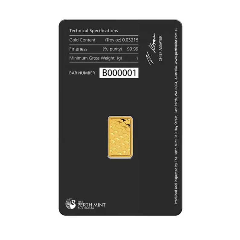 May include: A small rectangular gold bar set in a black assay card. The card displays technical specifications including Gold Content 0.03215 Troy oz, Fineness 99.99%, and Minimum Gross Weight 1 g. The bar number B000001 is printed on the card.