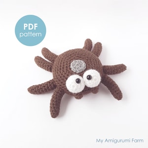May include: A crocheted brown spider with large white eyes and a gray spot. The spider has eight legs and is lying on a white surface. The image includes a blue circle with the text "PDF pattern". The text "My Amigurumi Farm" is also visible.