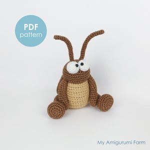 May include: A handmade crochet insect toy in brown and tan. The amigurumi bug has large white eyes, long antennae, and a round body. The text "PDF pattern" is in a blue circle. The words "My Amigurumi Farm" are at the bottom.