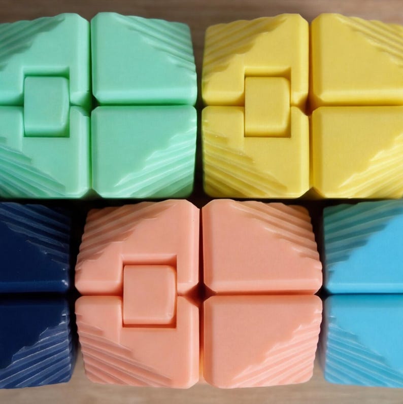 May include: Close-up of several colorful fidget toys. The toys are made of plastic and come in various colors, including green, yellow, peach, blue, and navy. Each toy is composed of four connected blocks with a textured surface.