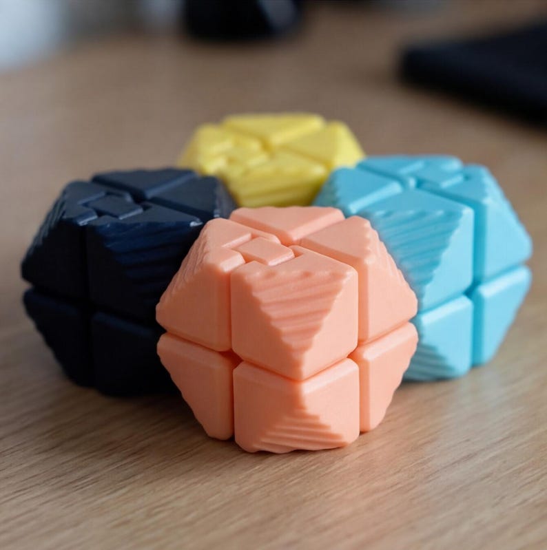 May include: A collection of colorful geometric puzzle toys in shades of navy, yellow, peach, and light blue. Each puzzle is composed of multiple interlocking pieces, creating a unique shape. The toys are arranged on a wooden surface.