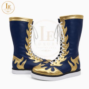 Peut inclure: Une paire de bottes hautes bleu marine avec des motifs dorés en forme de flammes et des bordures dorées. Les bottes ont des lacets et des semelles blanches. Les bottes sont étiquetées "Luxury Footwear".