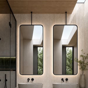 May include: A bathroom vanity featuring two oval stone sinks mounted on a floating concrete countertop. Above the sinks are two rectangular mirrors with black frames and integrated LED backlighting, suspended from the ceiling by black metal rods.