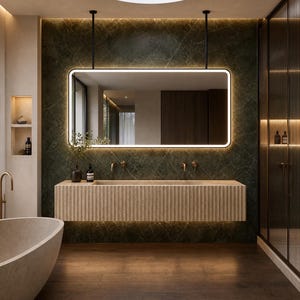 May include: A rectangular wall-mounted vanity with a fluted light-colored stone front and a long integrated basin. Above it hangs a large rectangular mirror with rounded corners and integrated LED lighting, suspended by two black metal rods.