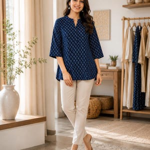 May include: A dark blue tunic featuring a white geometric pattern, a notched neckline, and three-quarter length sleeves, paired with solid beige trousers. The tunic has a relaxed fit and a straight hemline that falls at the hip, while the trousers are slim-fitting.