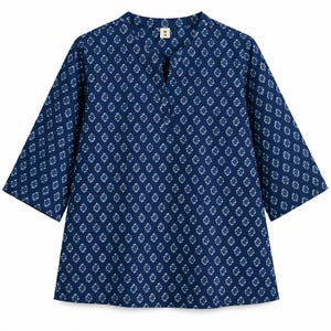 May include: A dark blue tunic with a repeating white diamond-shaped geometric pattern. The garment features three-quarter length sleeves, a split neckline, and a small white tag at the inner collar with the letter M printed in black.