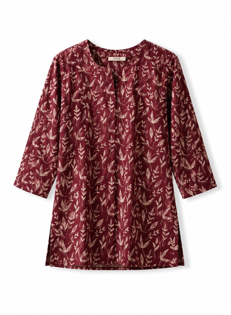 May include: A deep burgundy tunic featuring a light beige botanical leaf pattern throughout. The garment has three-quarter length sleeves, a round neckline with a small centre slit, and side hem vents. The interior label reads VIVE.