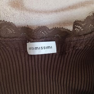 K&ouml;nnte beinhalten: Nahaufnahme eines braunen Ripp-Tanktops mit Spitzenbesatz. Auf dem Etikett steht "intimissimi" in einem wei&szlig;en Rechteck. Das Oberteil besteht aus einem weichen, gerippten Material.