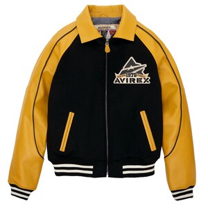 May include: Black and yellow varsity jacket with a zip-up front. The jacket features yellow leather sleeves and collar, with a black body. The front has two yellow pockets and a logo patch that reads "AVIREX 1975 CLASSIC". The cuffs and hem are striped.