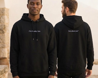 May include: A black hooded sweatshirt featuring the white text i'm choosing love. on the front chest and the white text how about you? on the back. The hoodie includes a front kangaroo pocket, long sleeves, and matching black drawstrings at the neck.