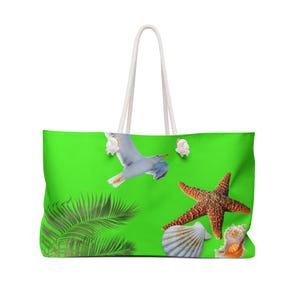 Puede incluir: Un bolso tote verde grande con asas de cuerda blanca. El bolso presenta un diseño de gaviota, estrella de mar, conchas marinas y hojas de palma. El bolso está diseñado para llevar lo esencial para la playa.