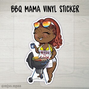 May include: A vinyl sticker featuring a cartoon illustration of a woman with red hair wearing sunglasses and an apron that says "Kiss the Cook". She is grilling food on a black grill.