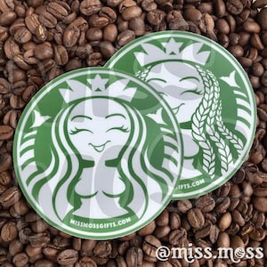 May include: Two green and white round stickers with a stylized female figure and a star on top. The stickers have the text "missmossgifts.com" and "@miss.moss" on them.