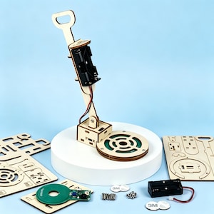Op de afbeelding: Een houten metaaldetector bouwpakket met een handvat, batterijhouder en cirkelvormige detectiespoel. De set bevat houten onderdelen, een printplaat, schroeven en een batterijpack. Gepresenteerd op een wit platform tegen een blauwe achtergrond.