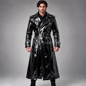 Op de afbeelding: Een lange, zwarte, glanzende trenchcoat met een dubbele rij knopen, zilverkleurige metalen ritsen, een brede kraag met inkepingen, schouderkleppen en een bijpassende riem met een zilveren gesp in de taille. De manchetten hebben verstelbare bandjes.