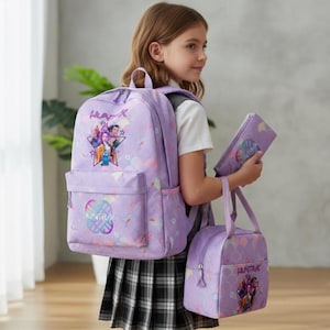Könnte beinhalten: Ein Set aus lavendelfarbenem Schulrucksack, Lunchbeutel und Federmäppchen. Jeder Artikel hat eine farbenfrohe Grafik und den Schriftzug "HUNTRAK". Das Set ist mit einem sich wiederholenden Muster aus Pastellregenbögen verziert.
