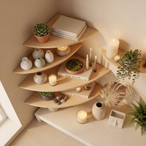 Pu&ograve; includere: Una mensola angolare con pi&ugrave; livelli che espone oggetti decorativi. I ripiani contengono piccoli vasi, candele, libri e piante in vaso. La palette di colori &egrave; neutra, con ripiani in legno naturale e pareti bianche.