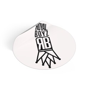 Puede incluir: Una pegatina circular blanca con un diseño gráfico negro. El diseño incluye el texto ROYAL BOYZ apilado sobre las letras RB, integradas en una forma de corona estilizada con puntas y extremos circulares en la base del diseño.
